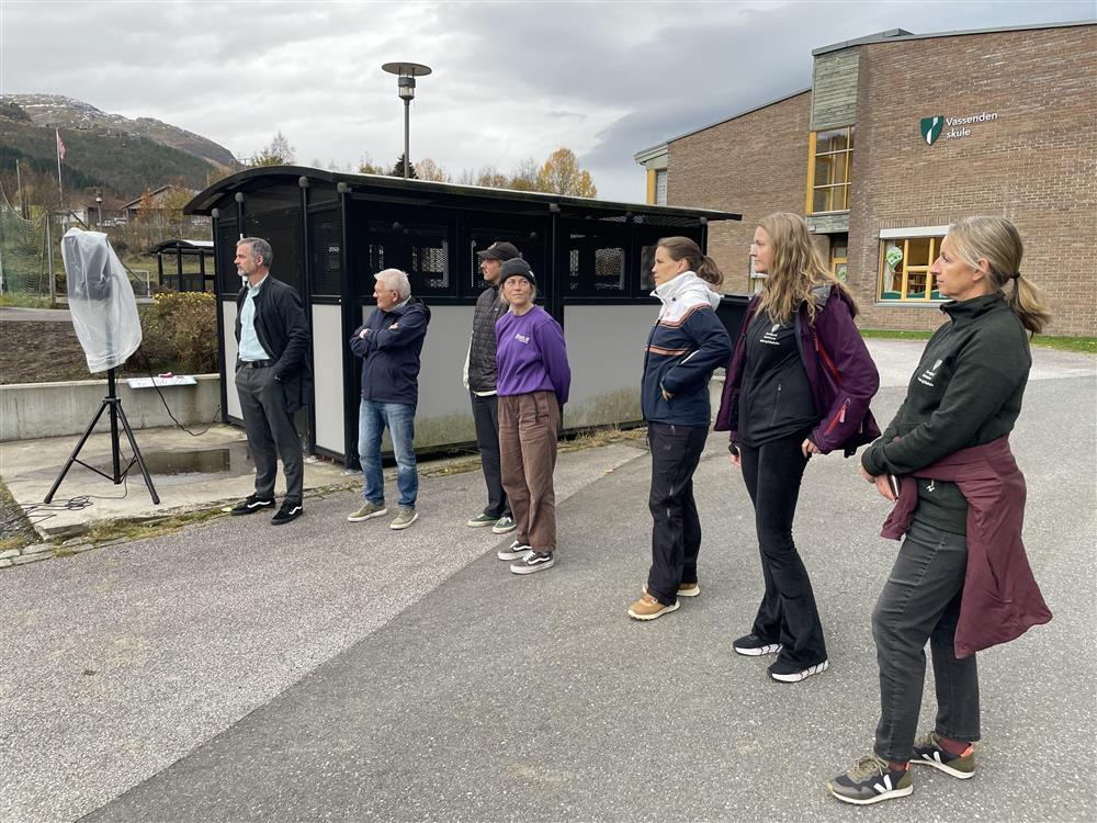 7 personar står og lyttar til talen ved opning av pumptrack - Klikk for stort bilete