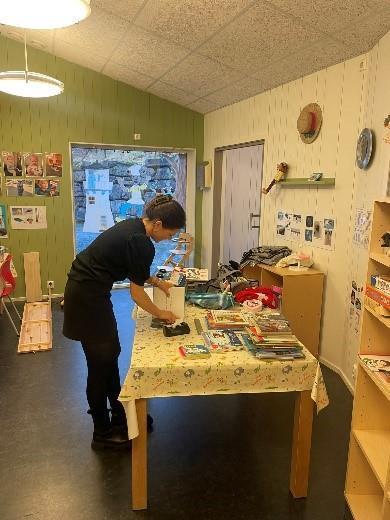 Ein person står ved eit bord og ryddar i bøker - Klikk for stort bilete